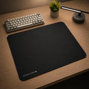 Esta imagem de close-up foca no canto inferior esquerdo do mouse pad, mostrando a costura da borda em detalhes. A costura preta e uniforme é claramente visível, indicando a alta qualidade da construção e a durabilidade. A textura da superfície de tecido também é visível, destacando a textura que fornece controle preciso do mouse. O logotipo "Meow Gaming Gear | ULTRABRAKE XL" está impresso de forma limpa e nítida em letras brancas. A iluminação suave e natural destaca a qualidade da construção e os detalhes.