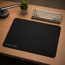 Vista diagonal e de ângulo do Mouse Pad Control Gamer Ultrabrake, demonstrando sua espessura e textura. A imagem foca em um close-up do mouse pad, capturando a textura da superfície de tecido com mais detalhes. As bordas costuradas e a costura preta e uniforme estão visíveis e nítidas, destacando a qualidade da construção. No canto inferior esquerdo, o logotipo "Meow Gaming Gear | ULTRABRAKE XL" está impresso de forma limpa e visível. Esta imagem é útil para mostrar a textura e a espessura do mouse pad.