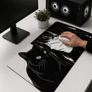 Vista superior de uma mesa branca com um monitor e um PC gamer de LED. No centro, é mostrado o Mouse Pad Grande Gamer Menina e Gato com detalhes em preto e branco com uma ilustração de estilo mangá de uma menina e um gato preto com olhos expressivos. Uma mão segura um mouse branco sobre o pad.