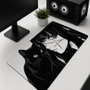 Visão superior angular do Mouse Pad Grande Gamer Menina e Gato estendido sobre uma mesa branca de configuração de PC. O mouse pad apresenta uma estampa detalhada em preto e branco de estilo mangá de um gato preto sentado com olhos expressivos e o rosto de uma menina com cabelos longos e cicatrizes faciais em forma de cruz. Um monitor e uma torre de PC gamer com ventoinhas de LED estão visíveis no fundo.