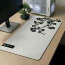 Mouse Pad Grande Gamer Sakura posicionado em uma mesa de madeira clara, destacando a estampa de ondas japonesas e o galho de cerejeira negra. A imagem mostra o produto em destaque, enfatizando o amplo espaço para teclado e mouse, com um gabinete gamer branco e um bonsai ao fundo.