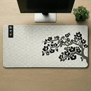 Visão superior de um Mouse Pad Grande Gamer Sakura (90x40cm) centralizado em uma mesa de madeira. A foto destaca a estampa completa de ondas estilo Seigaiha e o galho de cerejeira negra, com a base de um monitor e um pequeno bonsai posicionados simetricamente na parte superior.