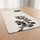Visão em ângulo em perspectiva do Mouse Pad Grande Gamer Sakura posicionado sobre uma mesa de madeira. A imagem destaca a estampa sutil de ondas japonesas e o design nítido de cerejeira negra, além de mostrar a espessura e o acabamento de qualidade do material. Ao fundo, uma janela com cortinas claras.