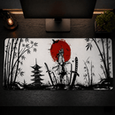 Uma foto aérea ("top-down") de uma mesa de madeira escura com um setup gamer, destacando o Mouse Pad Grande Gamer Samurai com design de arte de tinta japonesa. No centro do mousepad branco está um sol vermelho vibrante e uma silhueta de samurai, cercado por katanas fincadas no chão, bambus nas laterais e um pagode japonês à esquerda. Acima estão um monitor preto de tela plana, uma lâmpada de filamento industrial estilo Edison e uma pequena planta de bonsai. A iluminação é quente e ambiente.