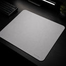 Uma vista aérea em ângulo do Mouse Pad Pk Control Gamer branco posicionado em um ambiente de jogo escuro com uma luminária linear no topo, teclado mecânico cinza ao lado e um pequeno vaso de planta. O mouse pad branco se destaca na superfície preta da mesa, mostrando seu tamanho e a textura da superfície de tecido.