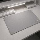 Mouse Pad Speed Gamer Galaxy Gem na cor cinza sobre uma mesa branca, ao lado de um teclado mecânico compacto. Ideal para um setup minimalista.