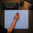 Pessoa utilizando um mouse preto sobre o Mouse Pad Speed Ultradash Blue. Visão superior em um setup limpo, destacando a superfície de deslizamento rápido do pad azul de 450x400mm, acompanhado por teclado mecânico e luminária ao fundo.