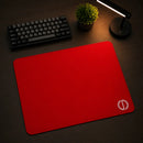 Foto em ângulo e perspectiva diagonal do Mouse Pad Speed Gamer Ultradash Red posicionado sobre uma mesa de madeira escura. O mouse pad de tecido vermelho destaca-se no cenário limpo, acompanhado de um teclado preto no canto superior esquerdo e uma luminária moderna com iluminação aconchegante.